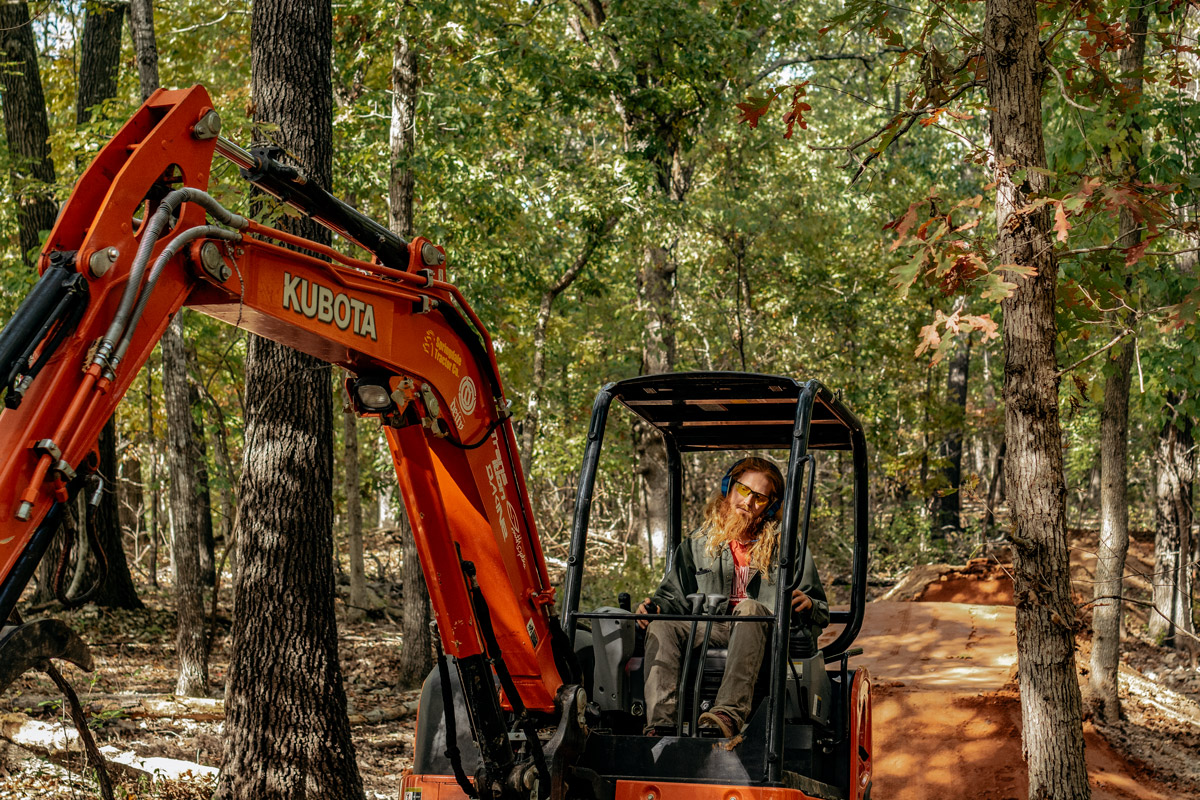 Progressive Trail Design crew member uses excavator to build trail